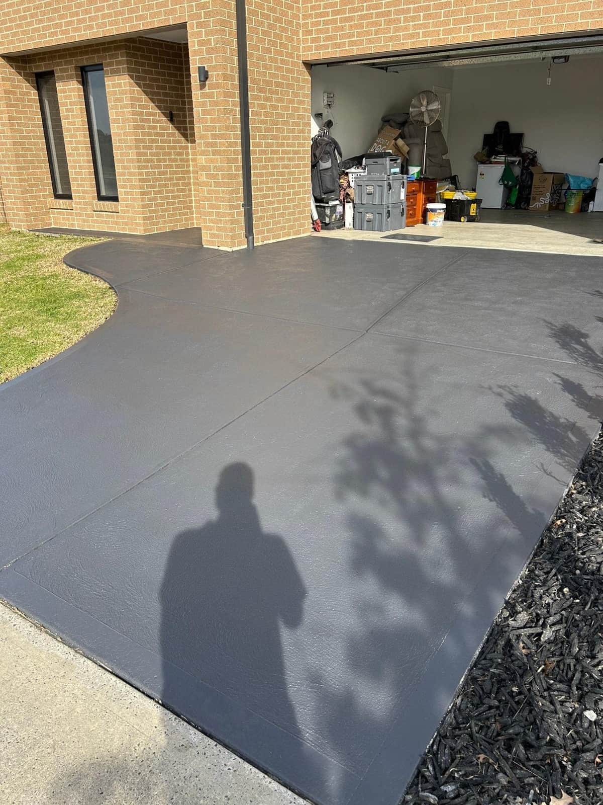 Shaded concrete driveway being pressure cleaned to remove winter moss and algae growth